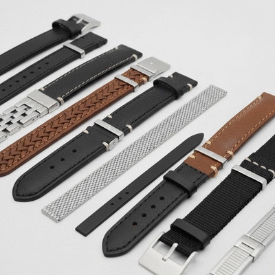 Close-up of various watch strap materials like leather, metal, and NATO fabric, neatly arranged