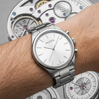 Close-up of a modern affordable watch on a wrist, with a blurred background of historical watch components