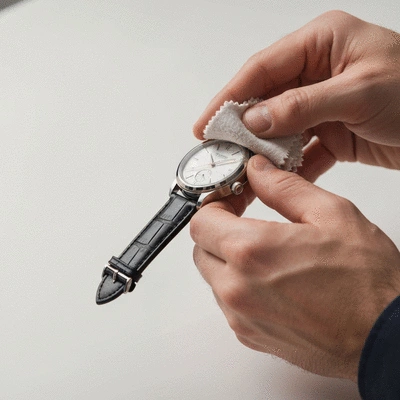 Close-up of a person cleaning a watch with a soft cloth